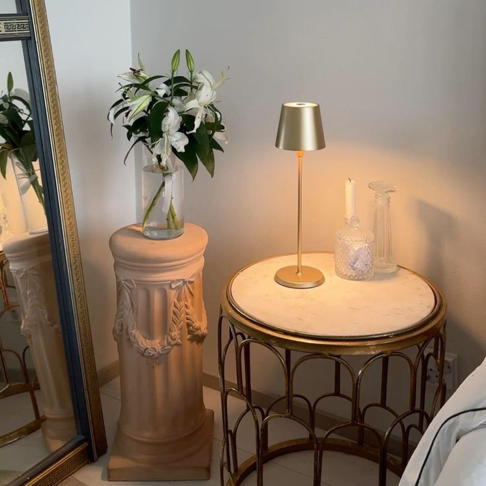 Selene - Table Lamp in champagne gold on a stylish side table with a vase of flowers and a candle.
